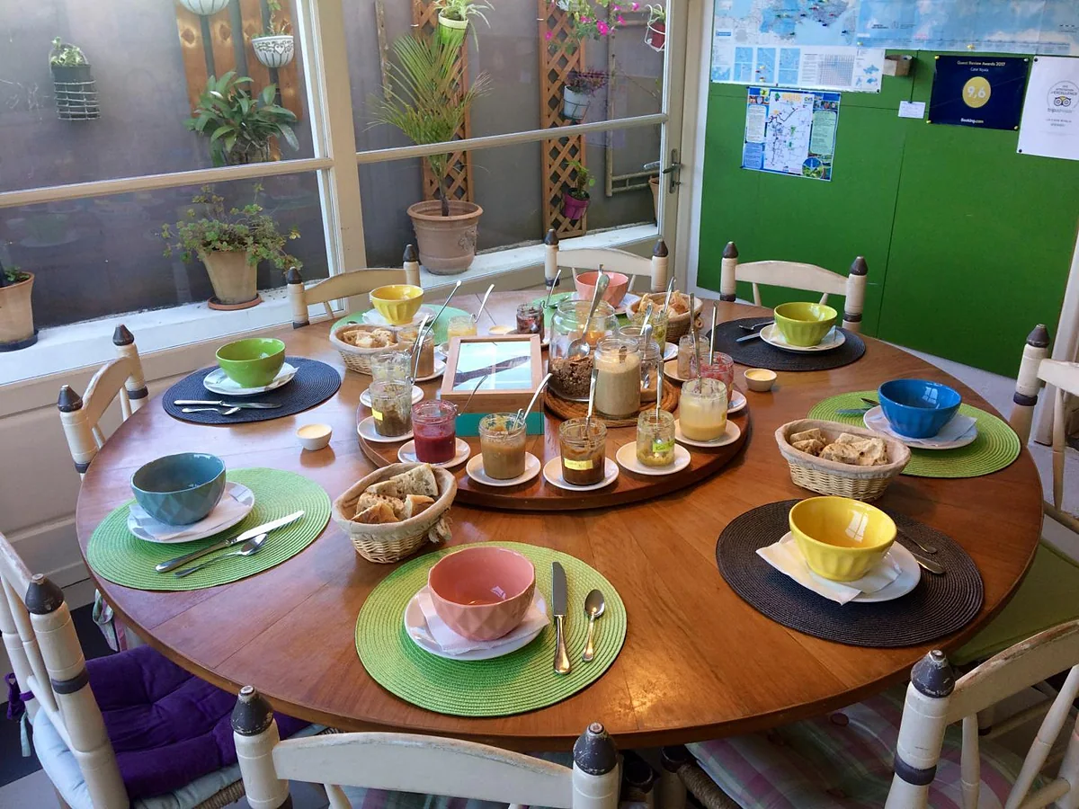 La table ronde du petit déjeuner, ses bols colorés et les pots de confiture